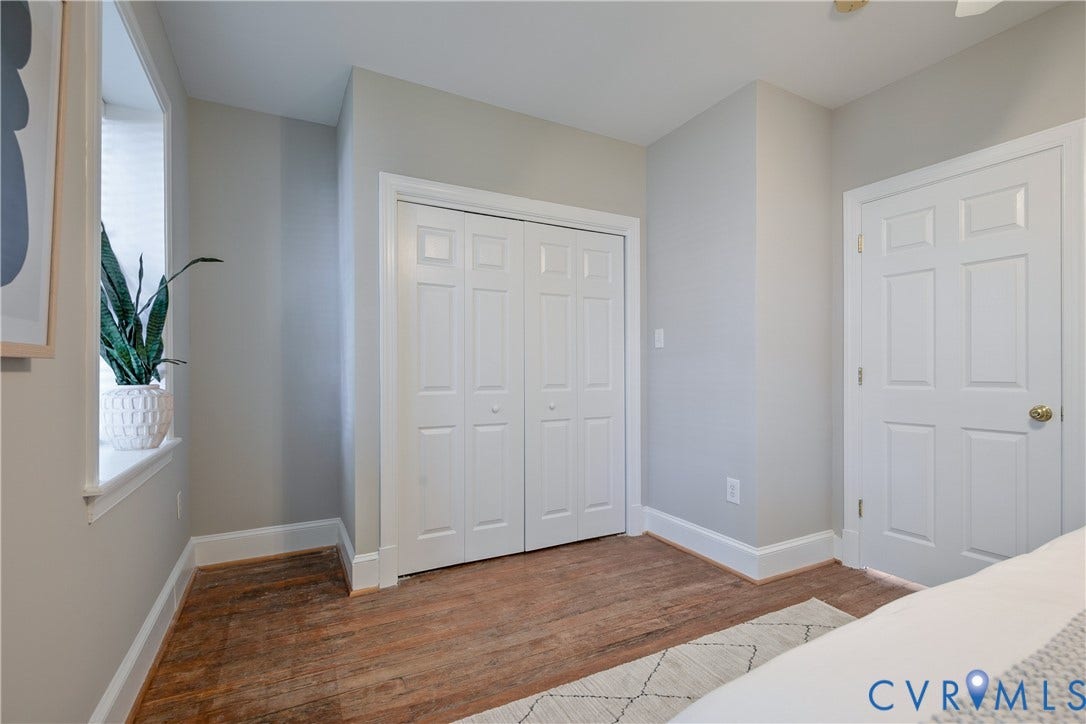 518 N 1st Street, Jackson Ward, Richmond, VA 23219 Wood-finish flooring with white trim, a window with privacy blinds, and white bi-fold closet doors