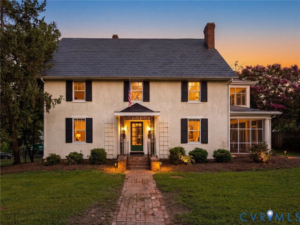 Classic Colonial residence showcasing a cream-colored exterior with black shutters, brick chimney, and slate roof