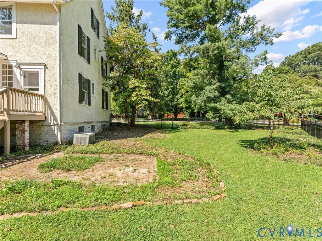 Expansive grounds featuring a manicured lawn with mature shade trees and established landscaping