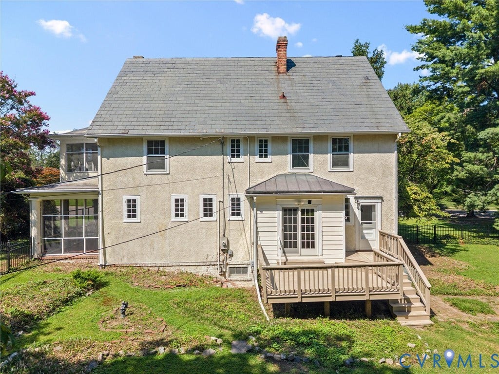 Classic two-story Colonial featuring a cream-colored exterior with slate-gray roof shingles, brick chimney, and multi-pane double-hung windows