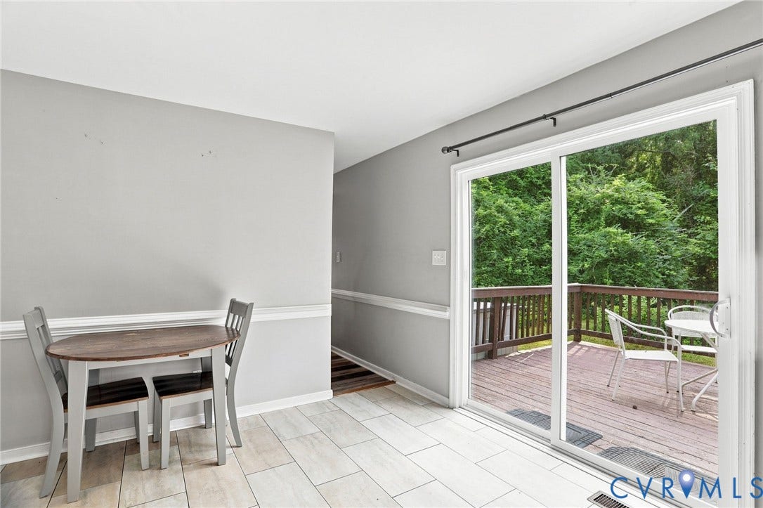 Sliding glass door leading to an outdoor deck, light-toned wall paint, and white trim molding