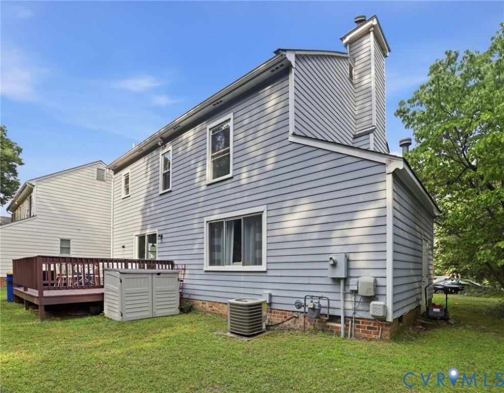 Wood deck with railing, siding exterior, multi-pane windows, and a prominent chimney feature