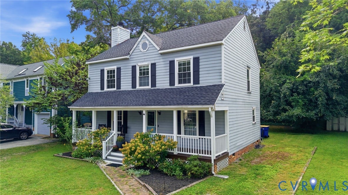 Two-story residence featuring light blue siding with dark shutters, a covered front porch, and a gable roof with a central dormer