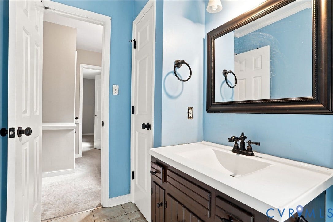 White integrated sink with a dark wood-finish vanity, framed mirror, and tile flooring