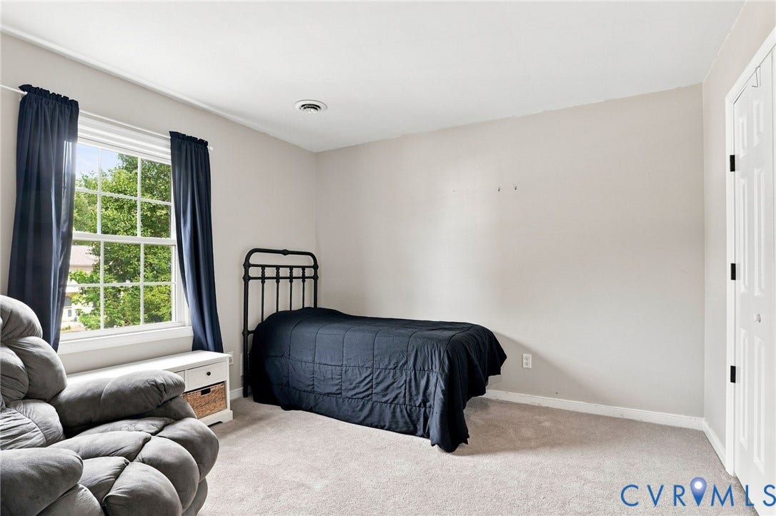Carpeted flooring, window with exterior scenery, built-in window bench with storage, ceiling-mounted vent, and bi-fold closet doors