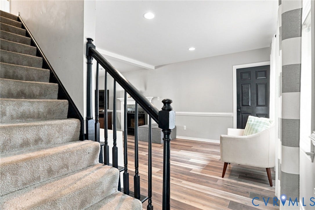 Carpeted stairway with black newel post and balusters