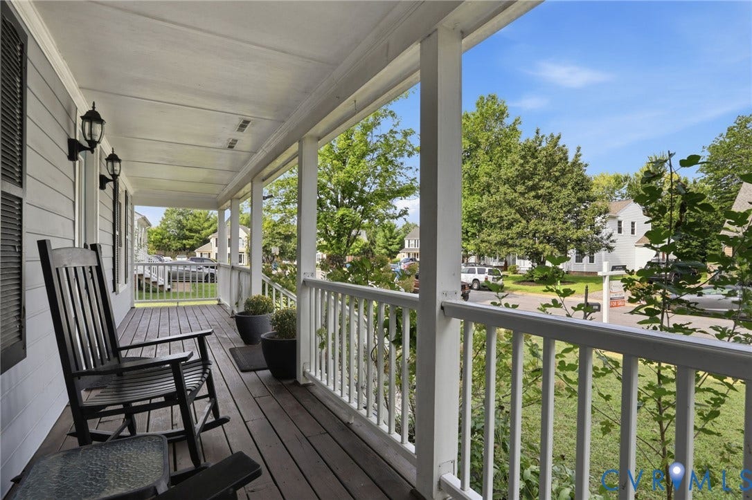 Covered front porch featuring wood-finish decking, white railings, and a shingled exterior