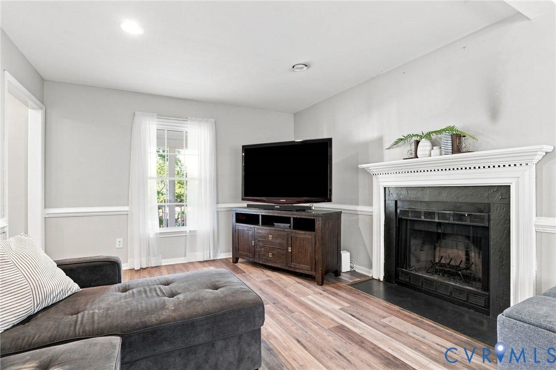 Wood-finish flooring, fireplace with a decorative mantel, crown molding, chair rail molding, and a window with natural light