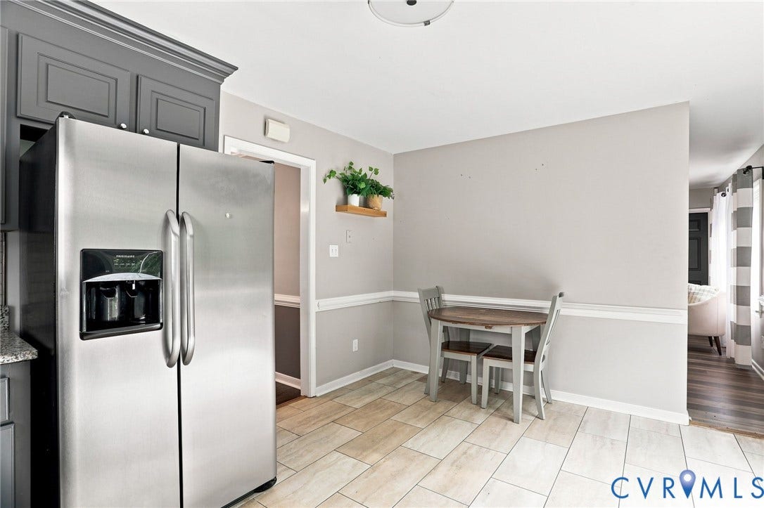 Wood-finish flooring with a tiled pattern, stainless steel refrigerator, and built-in cabinetry