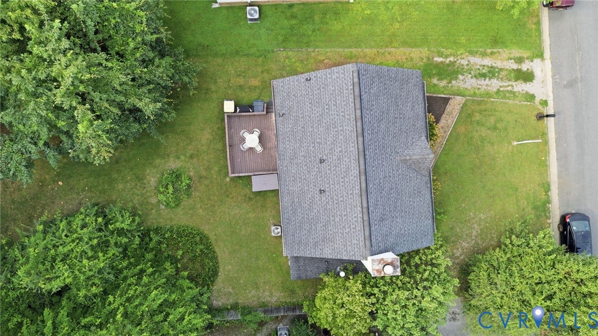Gabled roofline, rear deck, mature trees, green lawn, paved road