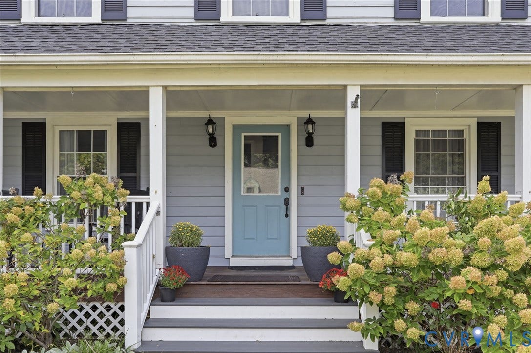 Covered front porch with light blue siding, a vibrant blue entry door, and dark exterior shutters