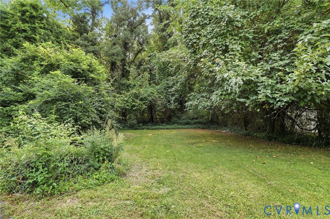 Expansive private grounds featuring a manicured lawn bordered by mature trees and lush hedgerow landscaping, offering generous outdoor space and natural privacy screening