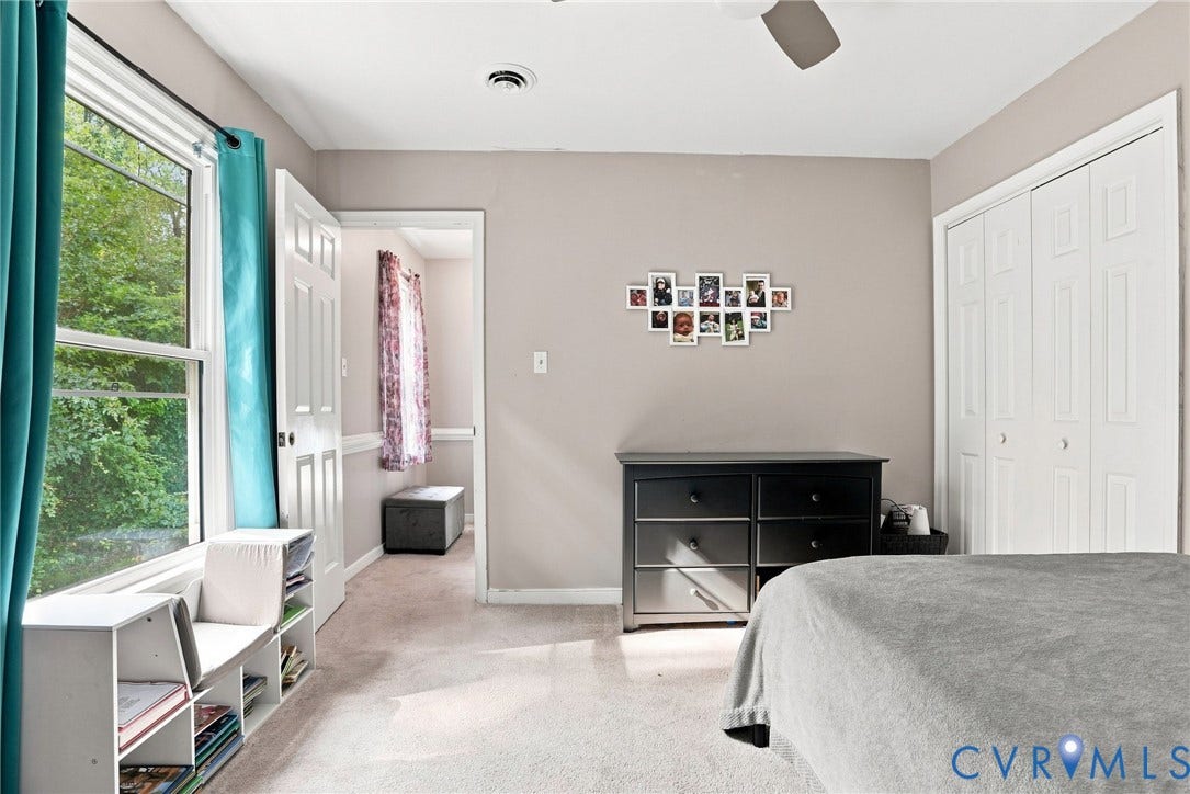 Wall-to-wall carpeting, white bi-fold closet doors, a white ceiling fan, and a built-in window seat with storage