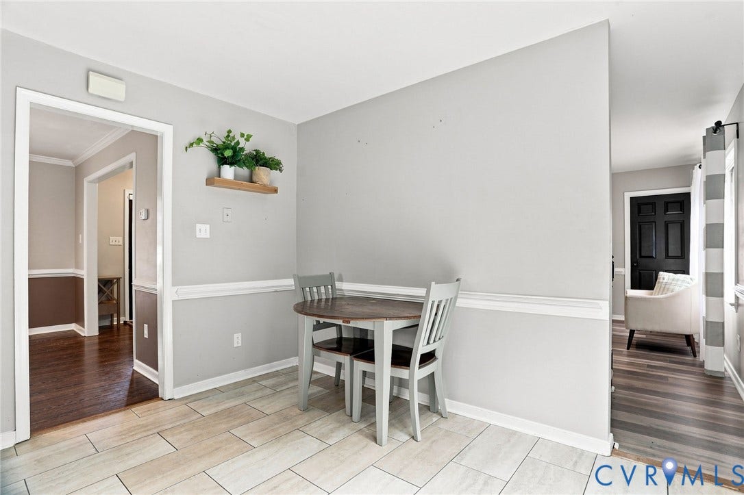 Light-toned tile flooring, chair rail molding, and a wall-mounted floating shelf