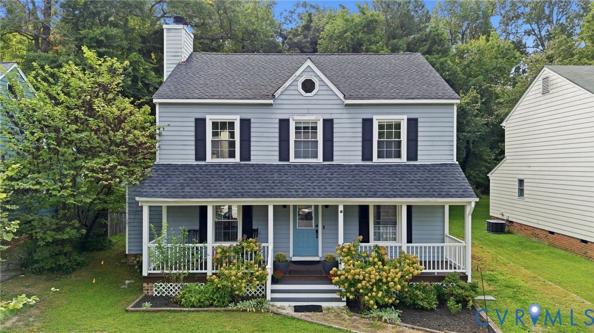 Two-story residence featuring light blue siding, a covered front porch, and dark shingle roofing