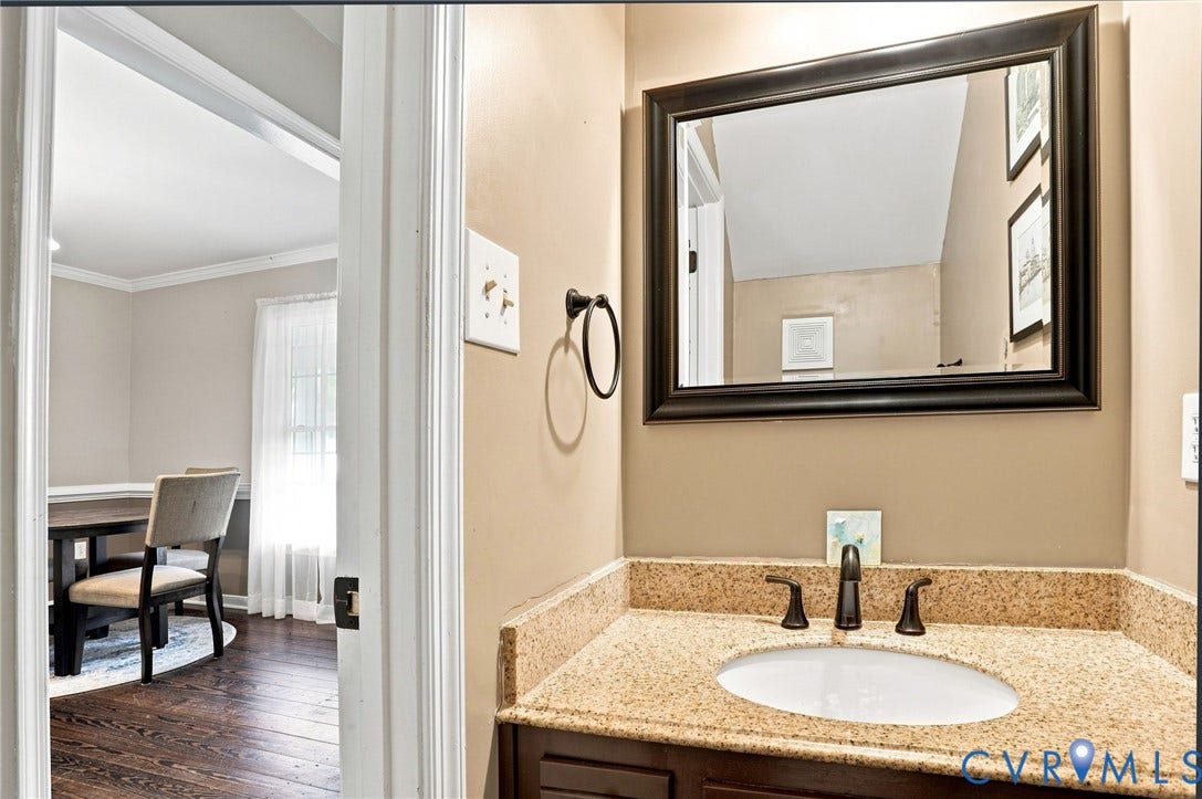 Vanity with granite countertop, undermount sink, and dark bronze fixtures
