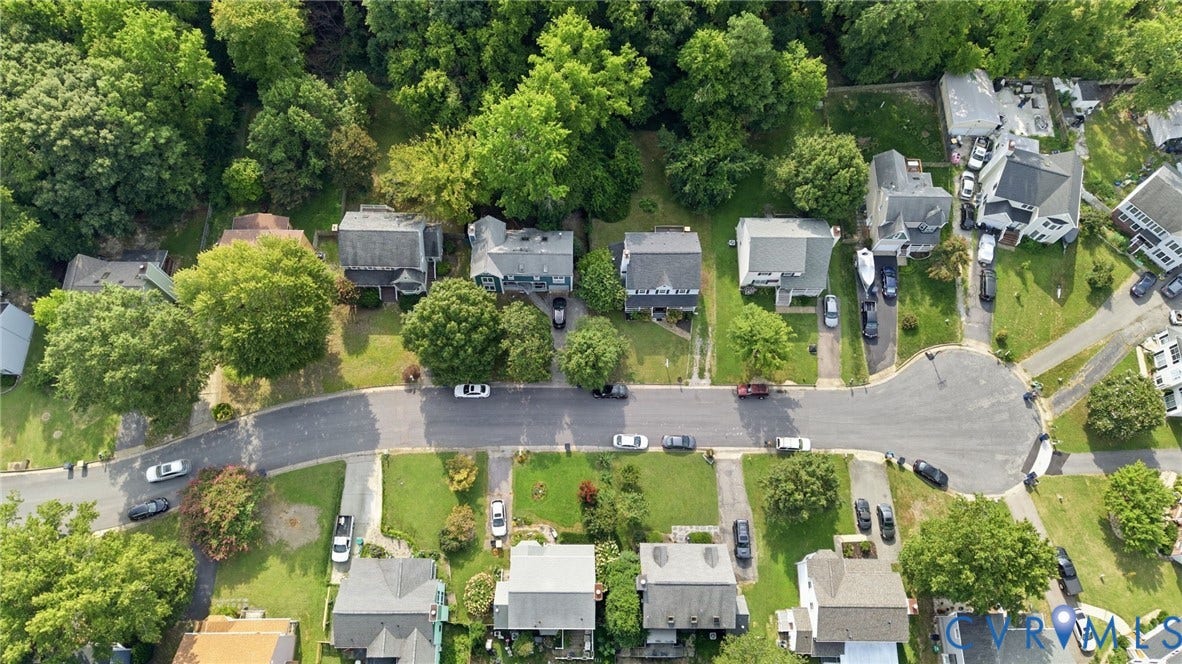 Residential street with established trees, paved roadways, and landscaped properties