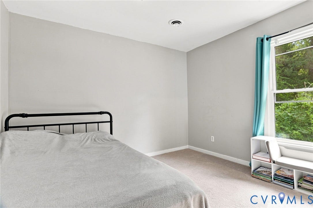 Neutral wall paint, carpeted flooring, a large window, and a built-in shelving unit