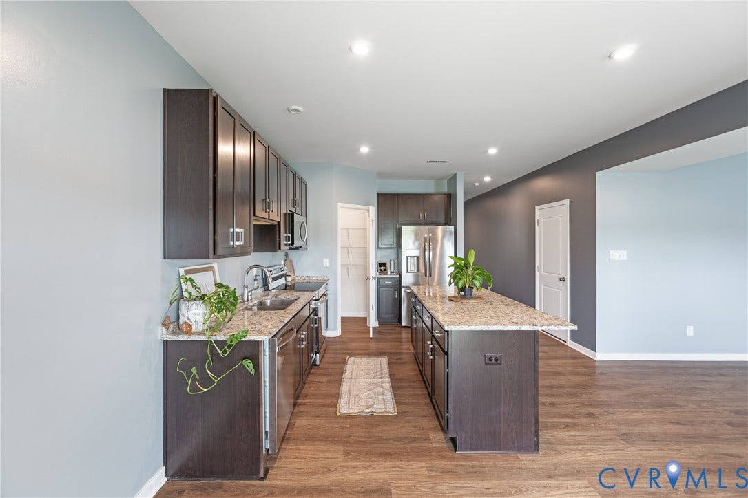 11419 Dunmore Mill Court, Chester, VA 23831 Kitchen featuring an extended island with granite-finish countertops, stainless steel appliances, dark wood-finish cabinetry, and wood-finish flooring