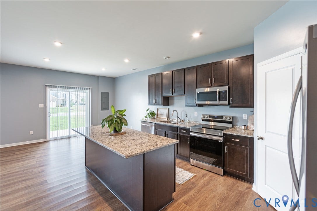11419 Dunmore Mill Court, Chester, VA 23831 Kitchen featuring wood-finish flooring, dark wood cabinetry, stainless steel appliances, and a central island with a stone countertop