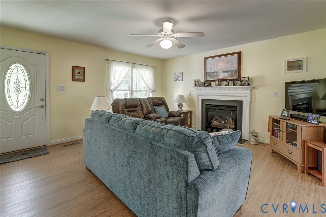 4229 Greenbriar Drive, Chester, VA 23831 Warm living area featuring wood-finish flooring, a ceiling fan with integrated lighting, and a fireplace with a white mantle