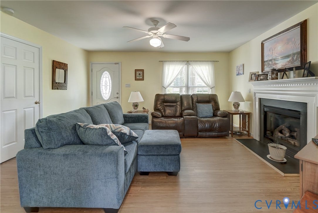 4229 Greenbriar Drive, Chester, VA 23831 Living area featuring wood-finish flooring, a fireplace with a white mantel, and a ceiling fan
