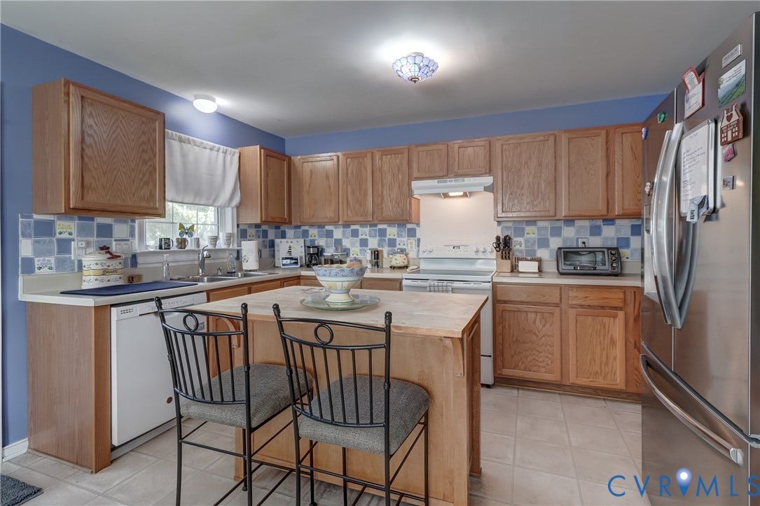 4229 Greenbriar Drive, Chester, VA 23831 Kitchen featuring wood-finish cabinetry, a central island with seating, stainless steel refrigerator, white appliances, and tiled flooring
