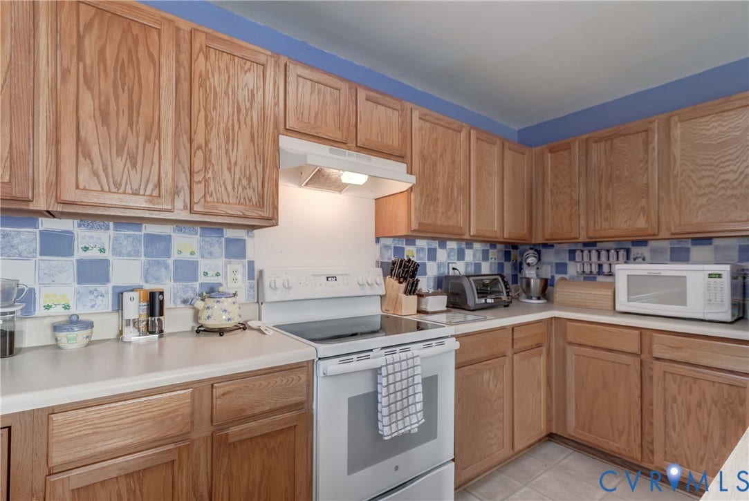 4229 Greenbriar Drive, Chester, VA 23831 Wood-finish cabinetry, light-toned countertops, white range, white range hood, and tile backsplash