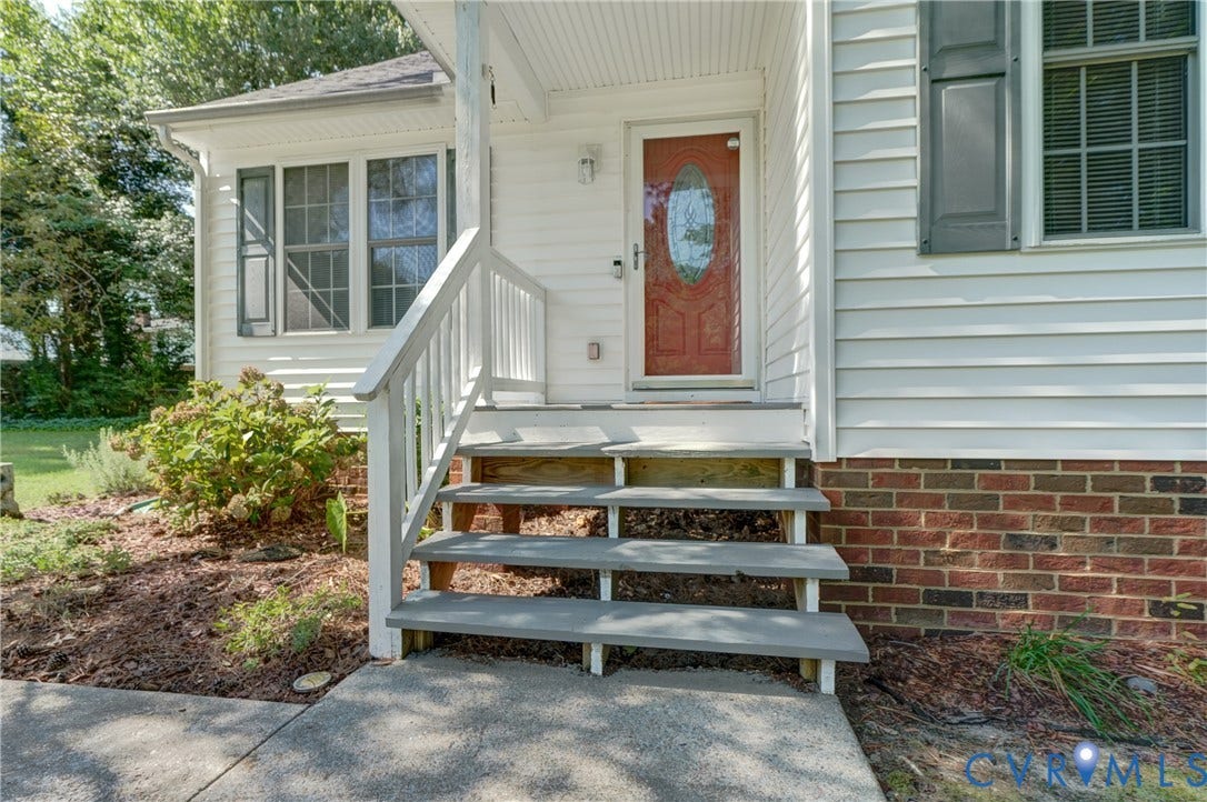 4229 Greenbriar Drive, Chester, VA 23831 Front entryway featuring a red door with decorative glass, white siding, and a brick foundation