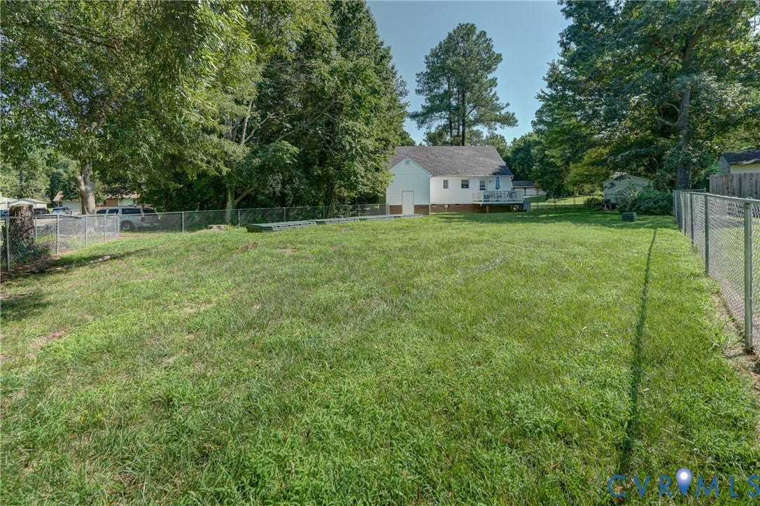 4229 Greenbriar Drive, Chester, VA 23831 Expansive backyard featuring a chain-link fence, mature trees, and a rear deck