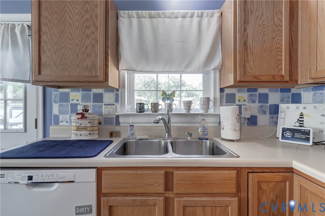 4229 Greenbriar Drive, Chester, VA 23831 Wood-finish cabinetry with a double basin stainless steel sink and a tiled backsplash