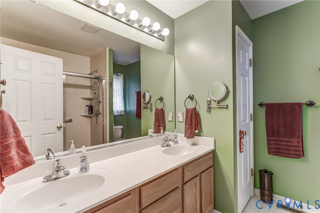4229 Greenbriar Drive, Chester, VA 23831 Dual vanity with integrated sinks, wood-finish cabinetry, and a full-width mirror with overhead bar lighting