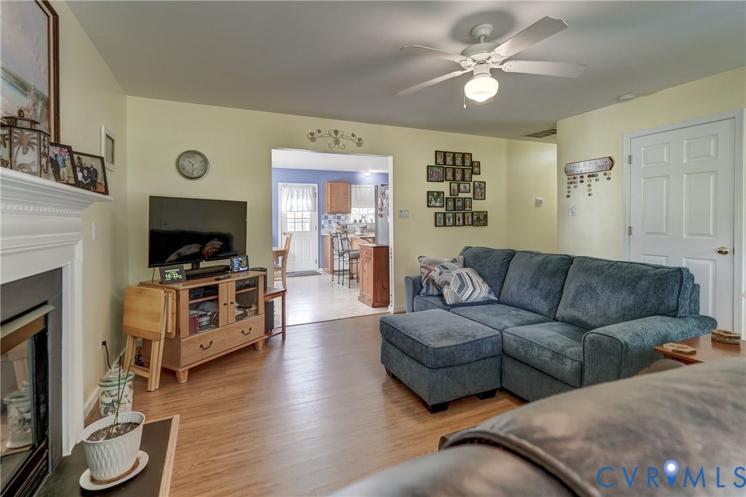 4229 Greenbriar Drive, Chester, VA 23831 Wood-finish flooring throughout, a white ceiling fan with integrated lighting, and a prominent white mantelpiece over the fireplace