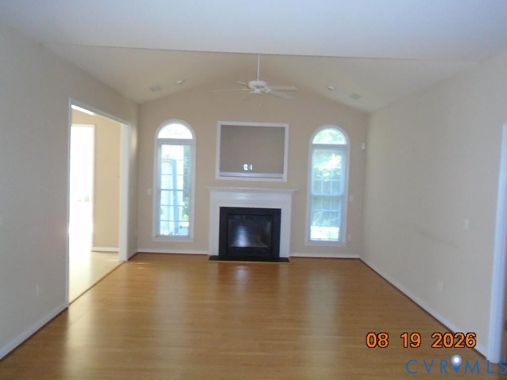 4113 Coles Point Way, Glen Allen, VA 23060 Spacious living area featuring vaulted ceilings, wood-finish flooring, a fireplace with a white mantel, and arched windows