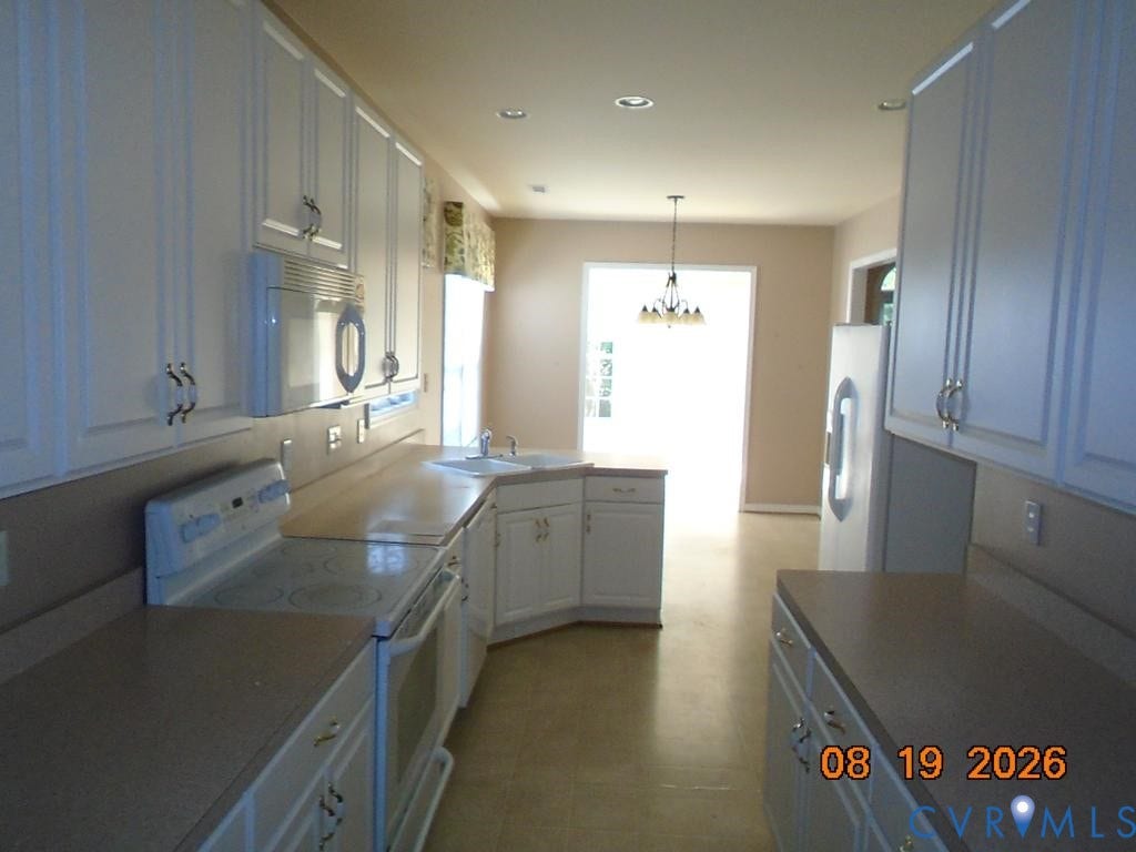 4113 Coles Point Way, Glen Allen, VA 23060 Expansive kitchen featuring white cabinetry, light-toned countertops, an integrated sink, an oven range, and a built-in microwave
