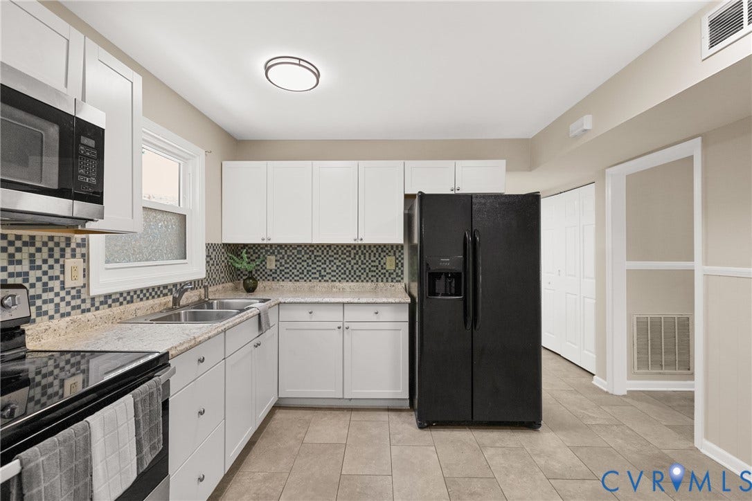 5401 Solaris Drive, Chesterfield, VA 23832 Bright, modern kitchen featuring white cabinetry, stainless steel appliances including a black side-by-side refrigerator, tile backsplash, granite countertops, and tile flooring