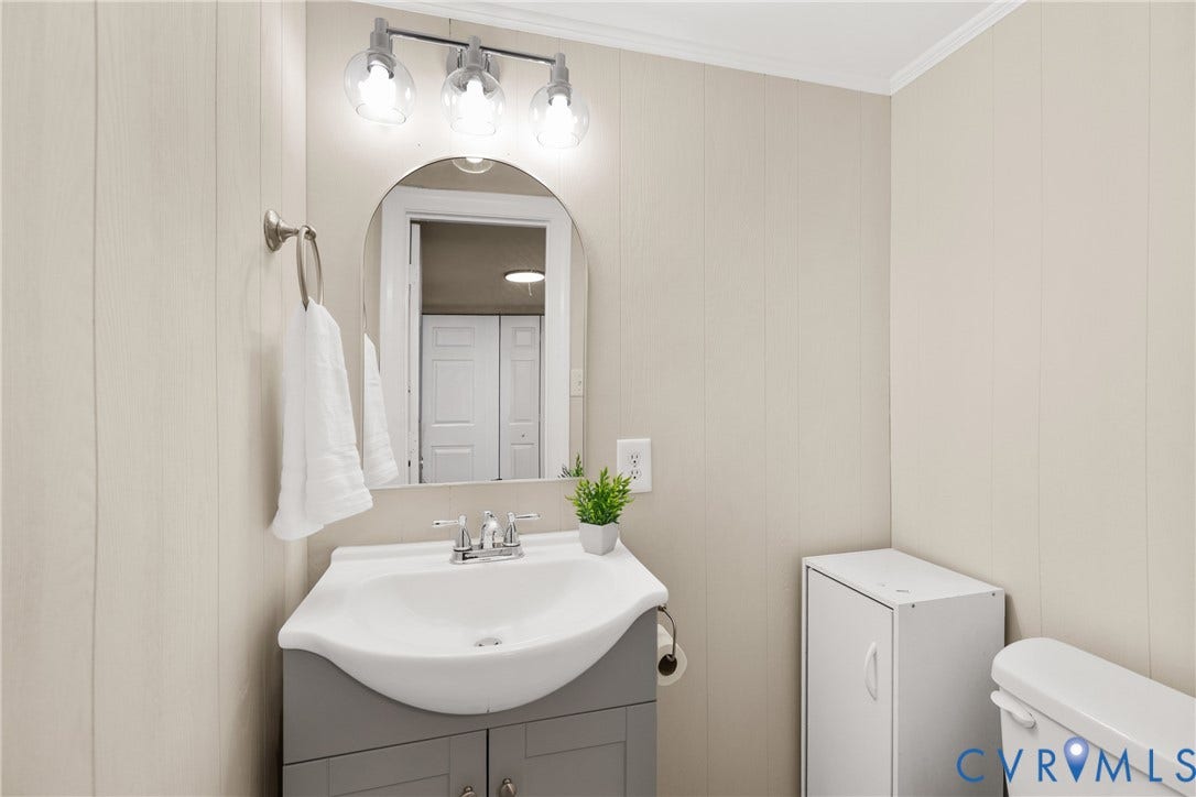 5401 Solaris Drive, Chesterfield, VA 23832 Pedestal-style vanity with gray cabinetry, a rounded mirror, and a three-light fixture