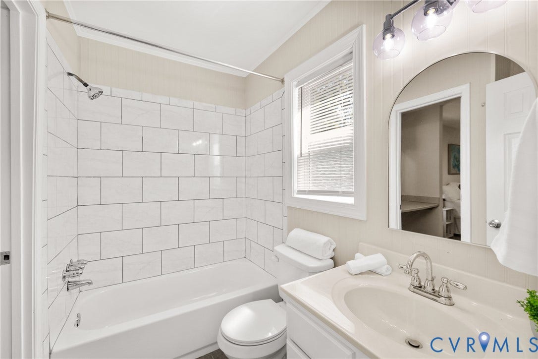 5401 Solaris Drive, Chesterfield, VA 23832 Bathtub with white subway tile surround, chrome fixtures, single vanity with integrated sink, arched mirror, and contemporary vanity lighting