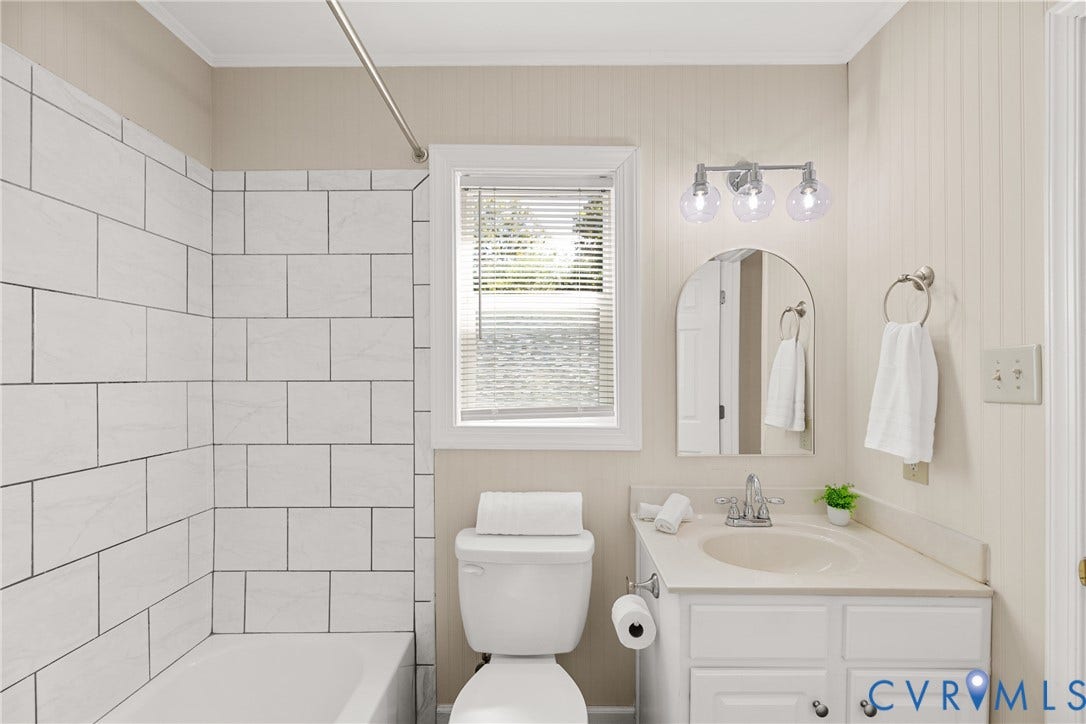 5401 Solaris Drive, Chesterfield, VA 23832 White subway tile shower surround, single window with blinds, white vanity with integrated sink, chrome faucet, and three-light vanity fixture