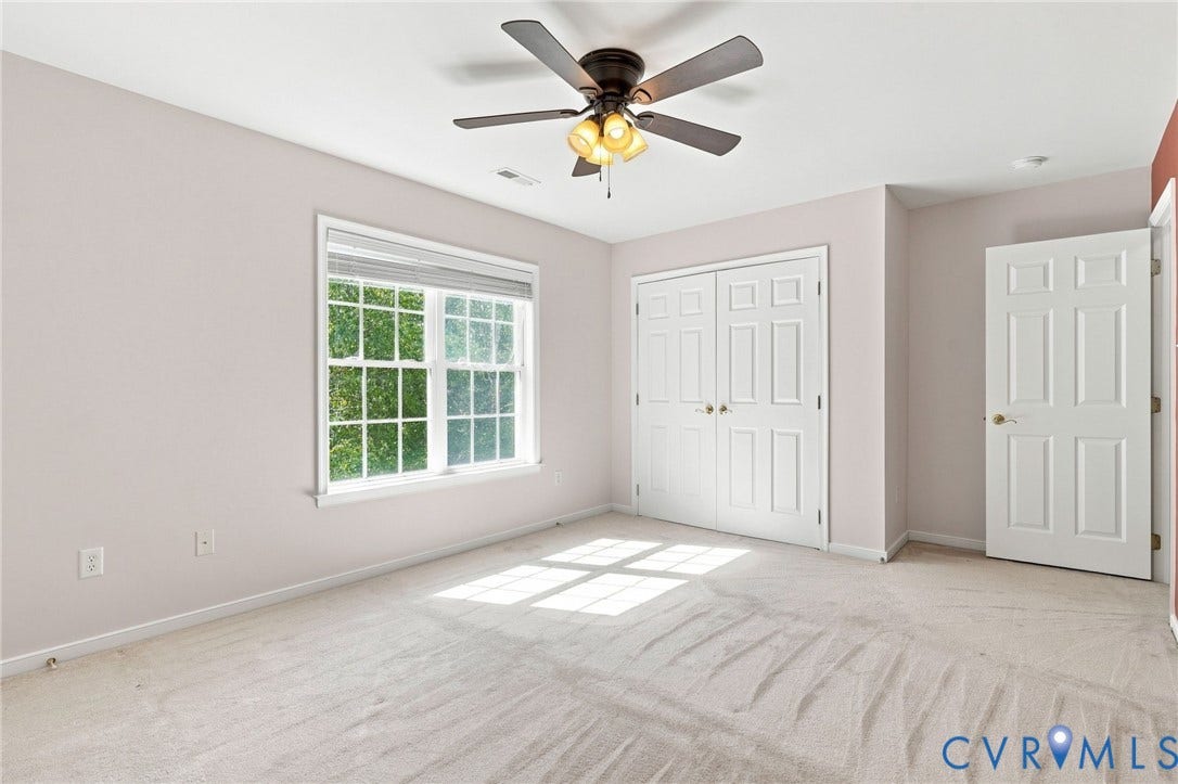 Window with white blinds, neutral carpet, ceiling fan with light fixture, and white paneled doors