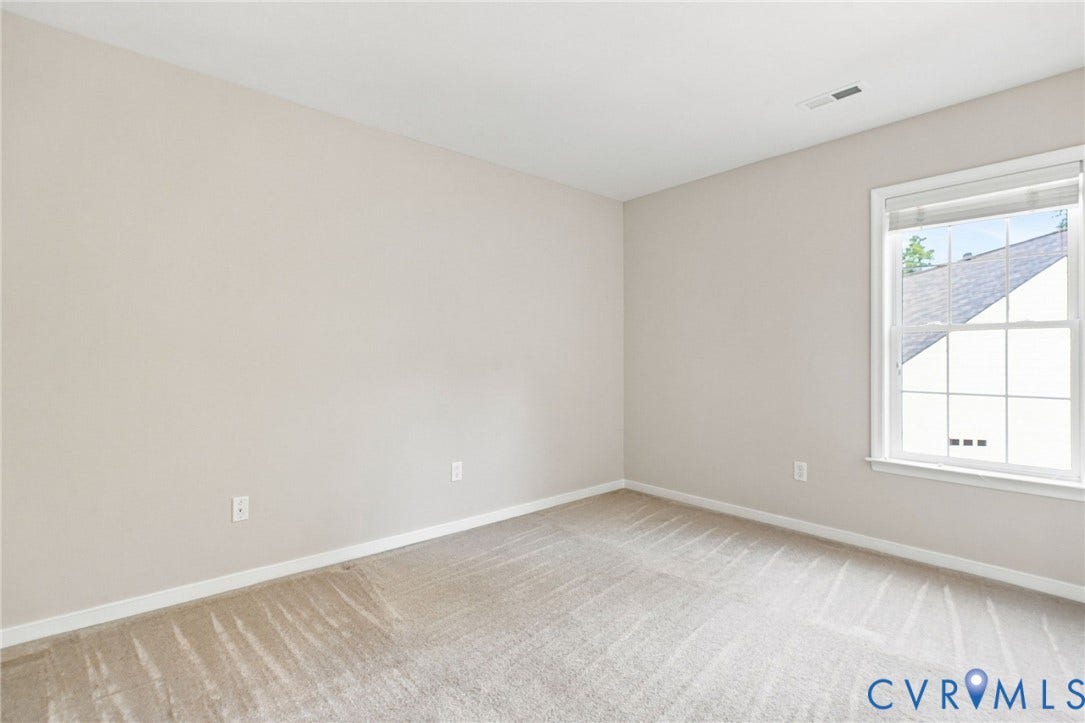 Carpeted room with neutral wall tones and a double-hung window