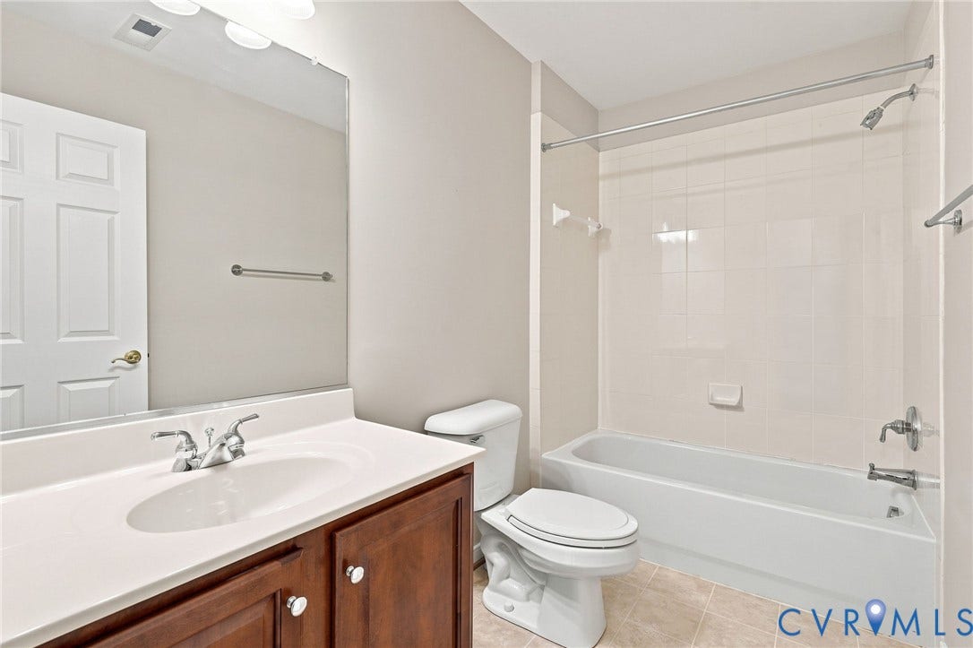 Vanity with an integrated sink, polished chrome faucet, wood-finish cabinetry, and a large wall-mounted mirror