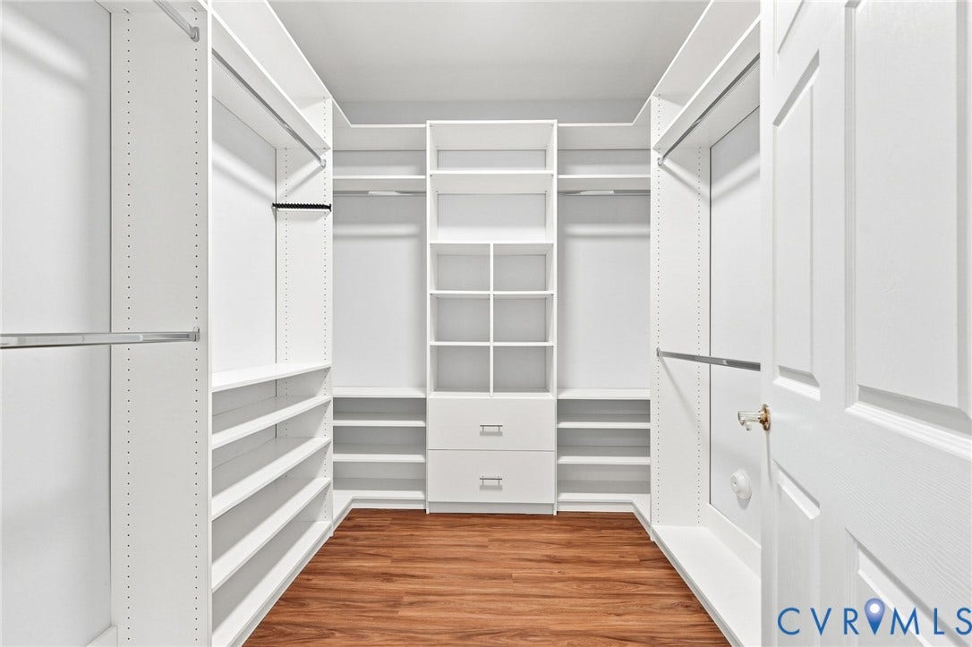 Custom closet system featuring white built-in shelving, integrated drawers, and ample hanging rods