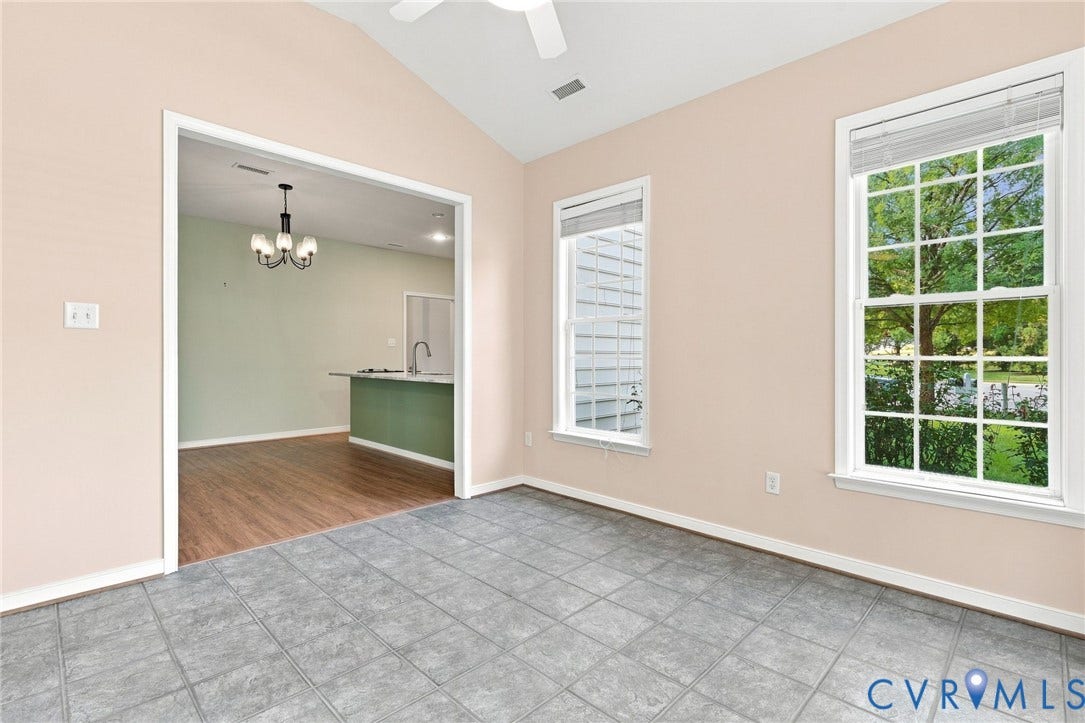 Vaulted ceiling with ceiling fan, tile flooring, and two double-hung windows
