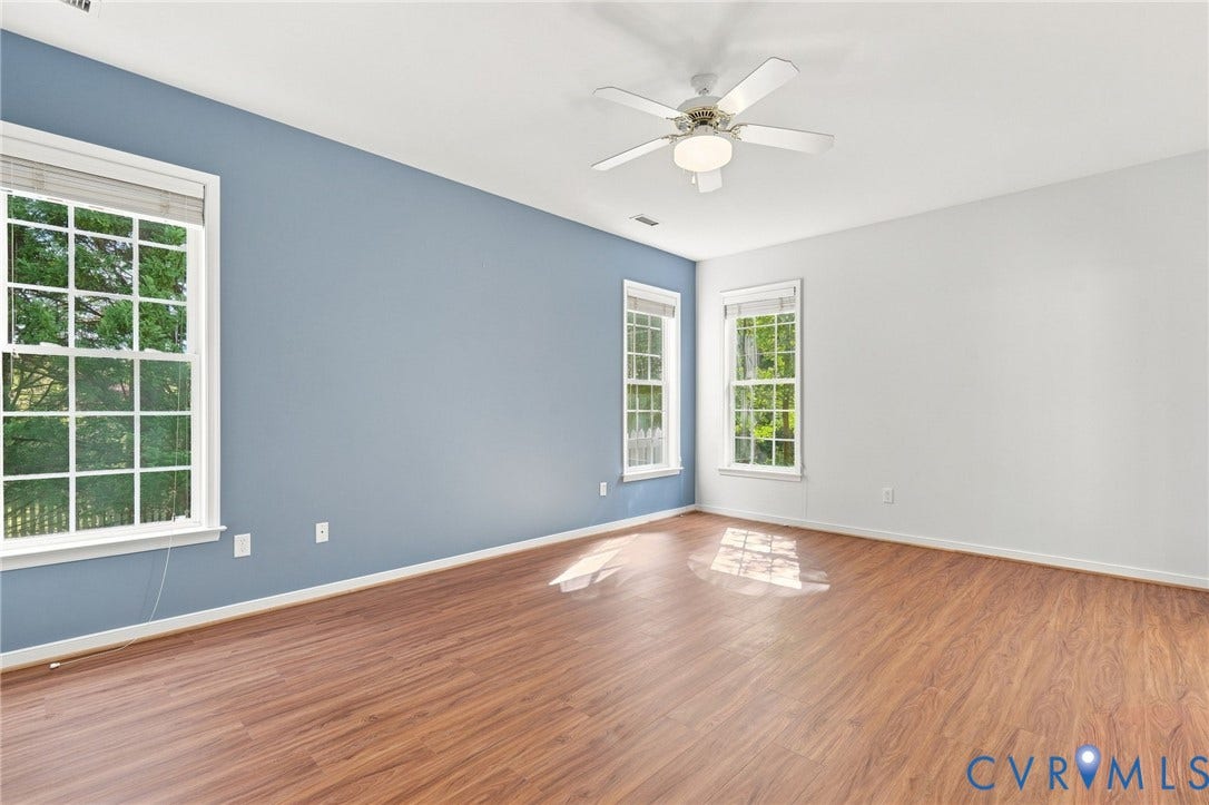 Wood-finish flooring with multiple windows and a ceiling fan