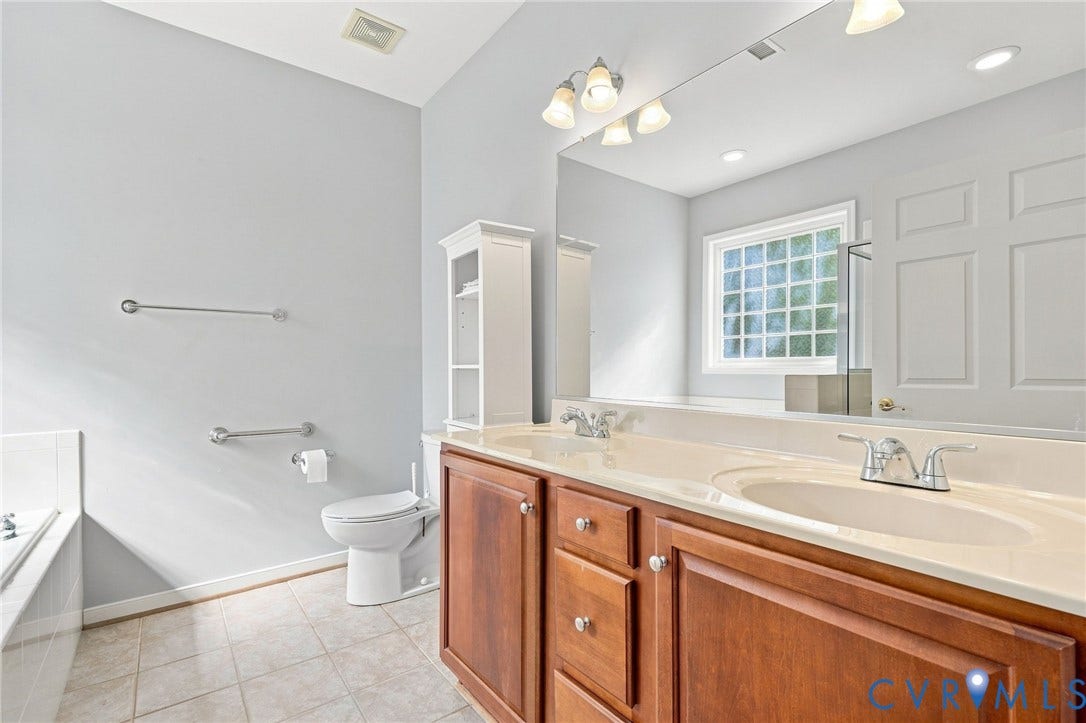 Dual vanity with integrated sinks, wood-finish cabinetry, and polished chrome fixtures