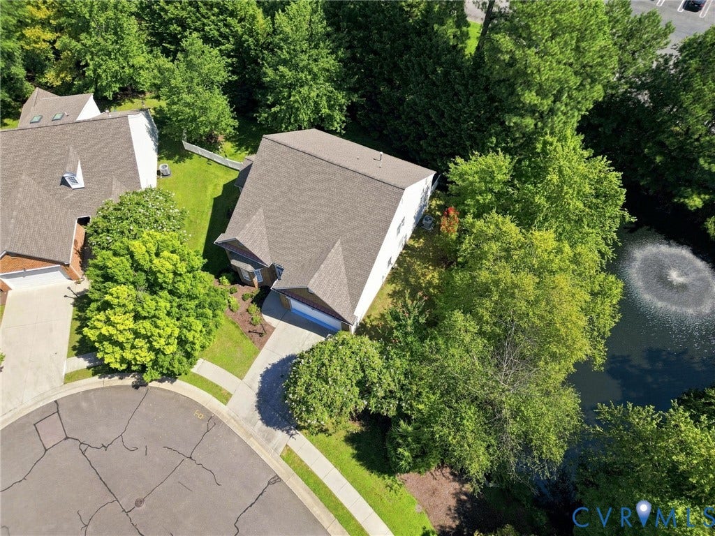 Property featuring a pitched roof, attached garage, concrete driveway, and landscaped grounds