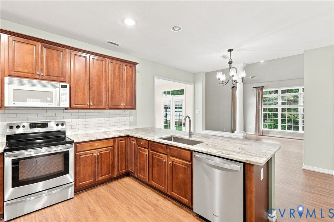 Kitchen featuring wood cabinetry, stainless steel appliances, a subway tile backsplash, and light-toned countertops