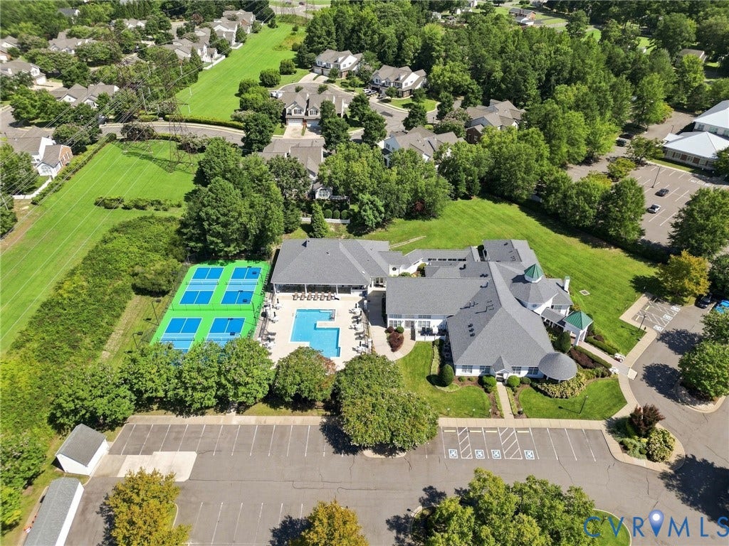 Clubhouse building with multiple gabled roofs, two tennis courts, an outdoor swimming pool, and dedicated parking areas