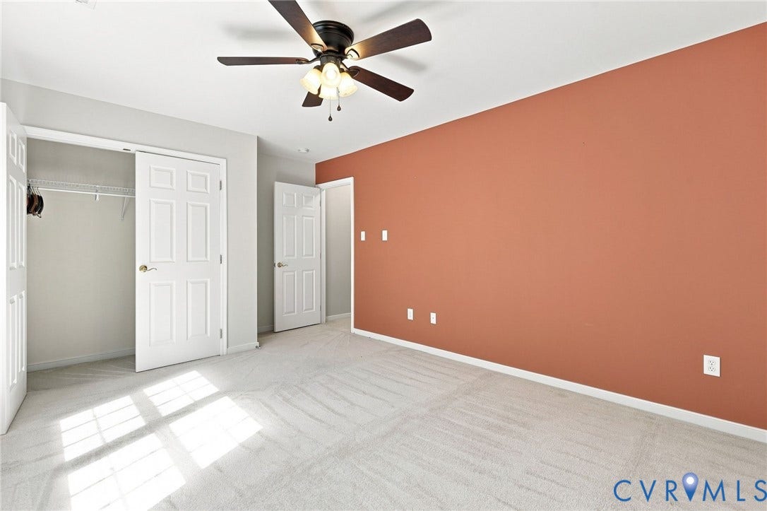 Plush carpeting with an overhead ceiling fan, white paneled doors, and a built-in closet with wire shelving
